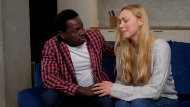 African American man comforting upset woman sitting on couch at home kitchen - Filmagem, Vídeo