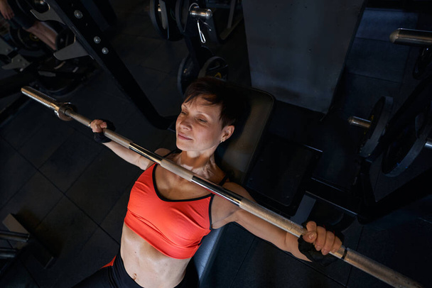Focused female bodybuilder performing incline bench press - Фото, зображення