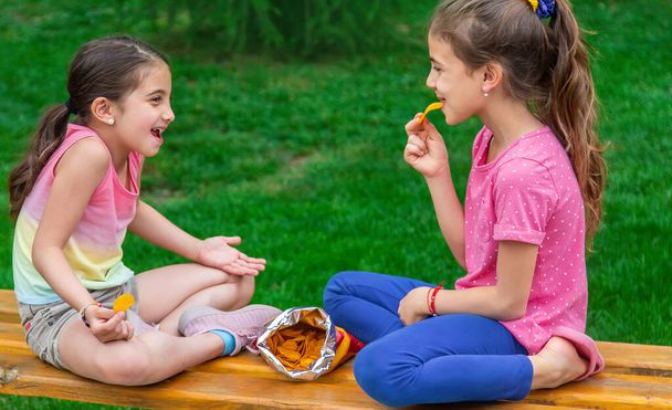Los niños comen patatas fritas en el parque de un amigo. Enfoque selectivo. Niños. - Foto, Imagen