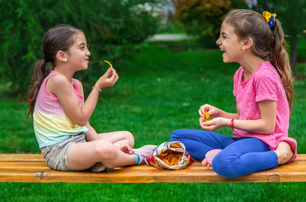 Los niños comen patatas fritas en el parque de un amigo. Enfoque selectivo. Niños. - Foto, Imagen