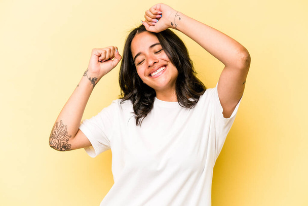Young hispanic woman isolated on yellow background celebrating a special day, jumps and raise arms with energy. - Photo, Image