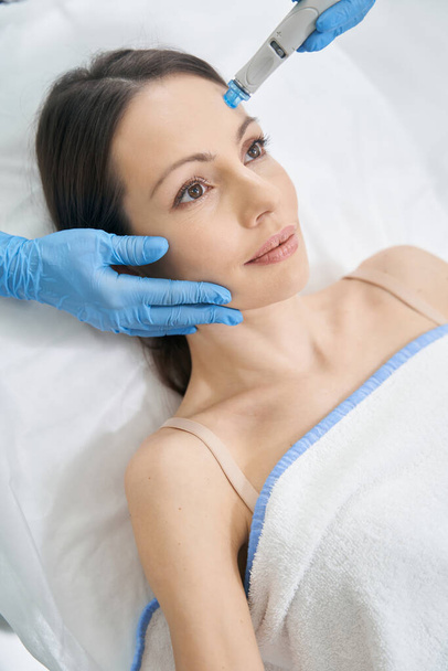 Vrouw met hydrafaciale huidverzorging procedure in schoonheidskliniek - Foto, afbeelding