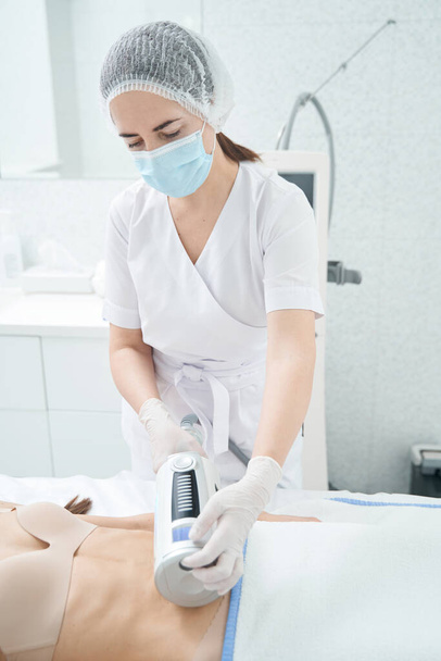 Cosmetologista feminino cuidadoso realizando massagem anti-celulite, removendo a flacidez da pele no abdômen - Foto, Imagem