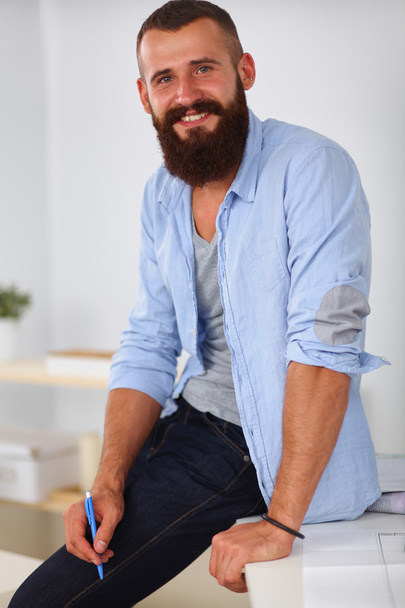 Portrait of male designer in hat with blueprints at desk - Foto, imagen