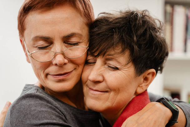Mature lesbian couple hugging and smiling at home - Фото, зображення