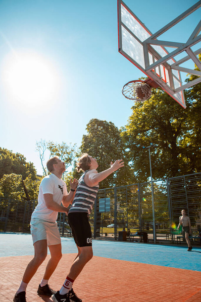 Lviv, Ukraine - May 12, 2022: men playing basketball outdoors copy space - Photo, image