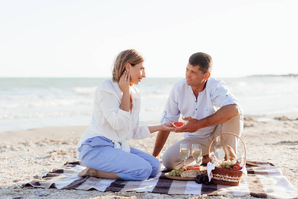 Szczęśliwa romantyczna para w średnim wieku na plaży. Piknik nad morzem. Podróże wakacje emerytury koncepcja stylu życia - Zdjęcie, obraz