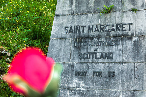 Lourdes, Francia - 18 maggio 2022: Iscrizione sotto la sua statua a Lourdes: Santa Margherita, regina e patrona della Scozia, prega per noi. - Foto, immagini