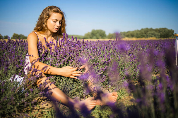 Relaxed pretty woman breathing fresh air sitting in a lavender field a sunny day - Photo, Image