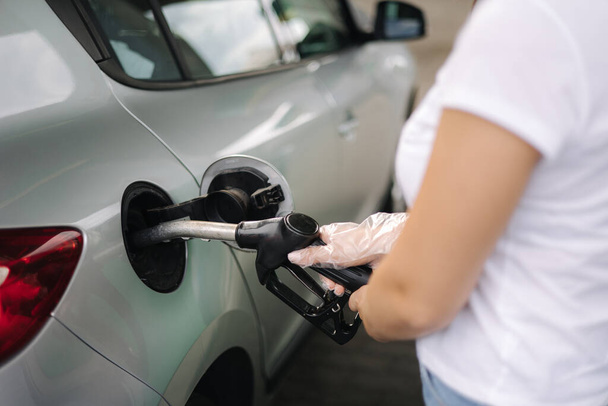 女性はガソリンスタンドで給油している。女性の手は、燃料ノズルを使用して車の中でベンジンガソリン燃料を充填。ガソリン価格の概念。手を閉じる。ウクライナの燃料不足 - 写真・画像