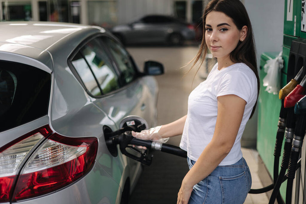 Kobieta tankuje na stacji benzynowej. Kobiece ręczne napełnianie benzyny benzynowej w samochodzie za pomocą dyszy paliwowej. Koncepcja cen benzyny. Niedobór paliwa na Ukrainie - Zdjęcie, obraz