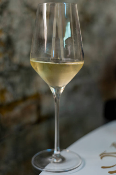 Degustación de vino espumoso de champán brut producido por el método tradicional en cuevas subterráneas de cerca - Foto, imagen