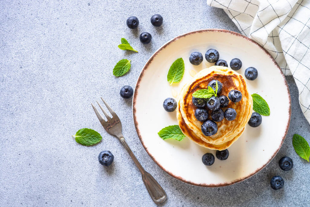 Pancakes stack with fresh blueberries and honey at stone table. Healthy breakfast or dessert. Top view with copy space. - Фото, зображення