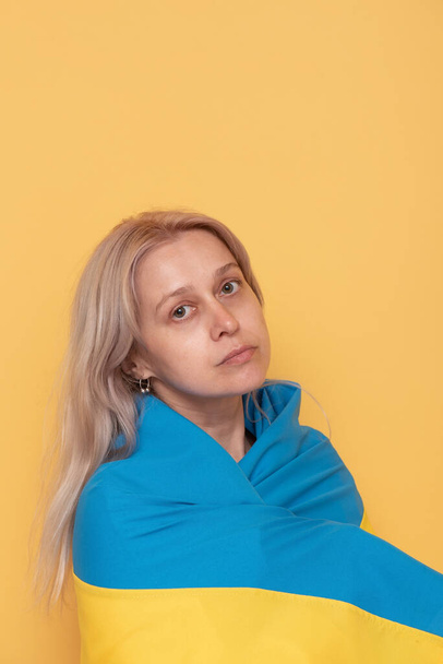 Portret kobiety. Kobieta z blond włosami z niebiesko-żółtą tkaniną na ramionach. - Zdjęcie, obraz