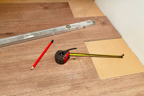 Tape meten en potlood liggen op de vloer, doe-het-zelf reparatie, parket leggen - Foto, afbeelding