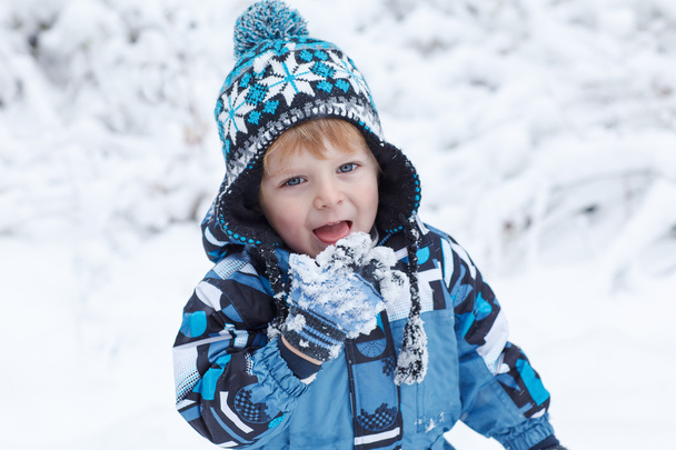 Adorable toddler boy having fun with snow on winter day  - Fotó, kép