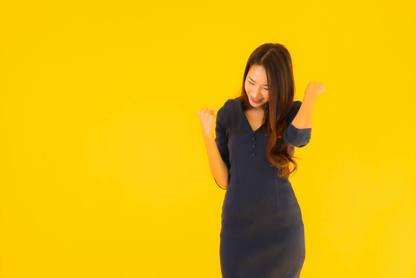 Portret mooie jonge aziatische vrouw met actie op geïsoleerde gele achtergrond - Foto, afbeelding