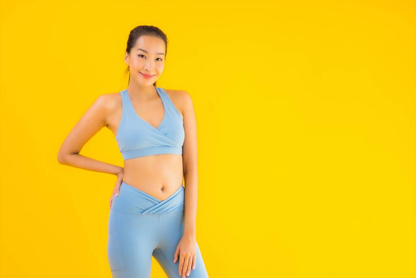 Портрет красива молода азіатська спортивна жінка зі спортивним одягом, готова до вправ на жовтому ізольованому фоні
 - Фото, зображення