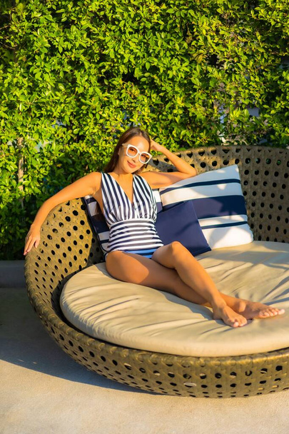 Retrato hermosa joven asiática mujer relajarse sonrisa ocio en vacaciones alrededor de la piscina en resort hotel - Foto, Imagen