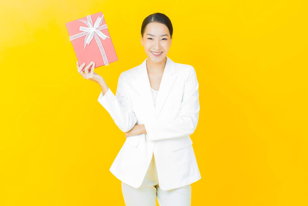 Portrait beautiful young asian woman smile with red gift box on color background - Fotografie, Obrázek