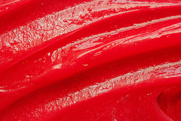 Red gel texture. Cosmetic clear liquid cream smudge. Skin care product sample closeup. Toothpaste or wax - Foto, imagen
