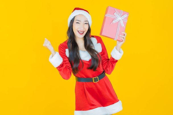 Retrato hermosa joven mujer asiática usar traje de navidad con caja de regalo roja en el fondo de color - Foto, imagen