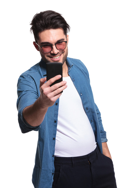 młody człowiek dorywczo uśmiechający się podczas pisania wiadomości SMS  - Zdjęcie, obraz