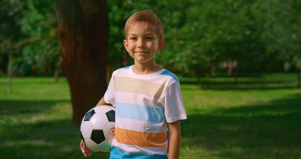 Topları doğaya gülümseyen küçük bir çocuk. Parktaki yakışıklı sporcunun portresi. - Fotoğraf, Görsel
