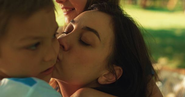 Liebende Mutter küsst Jungen beim Picknick aus nächster Nähe. Glückliche Frau zeigt liebevolle Kinder. - Foto, Bild