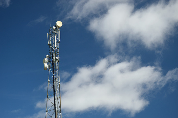 Telecommunicatie toren met blauwe lucht en de wolken in de achtergrond - Foto, afbeelding