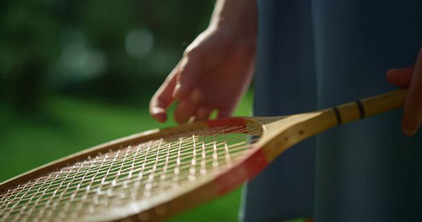 Een close-up kinderhand die badminton racket onderzoeksnet vasthoudt. Actief hobby concept - Foto, afbeelding