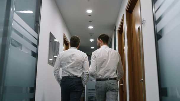 Twee zakenman lopen kantoor bespreken bedrijfsgegevens samen in finance bedrijf. - Foto, afbeelding