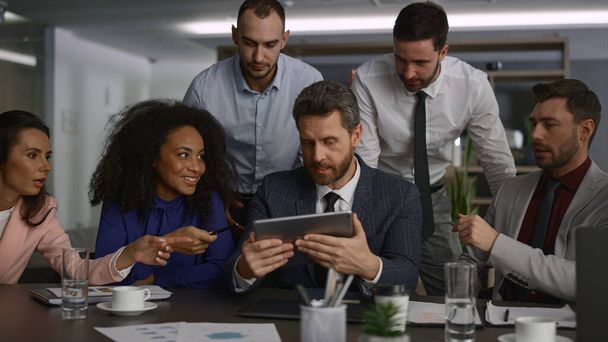 Equipo ejecutivo diverso que analiza datos usando el dispositivo de tableta en la reunión de la oficina. - Foto, imagen