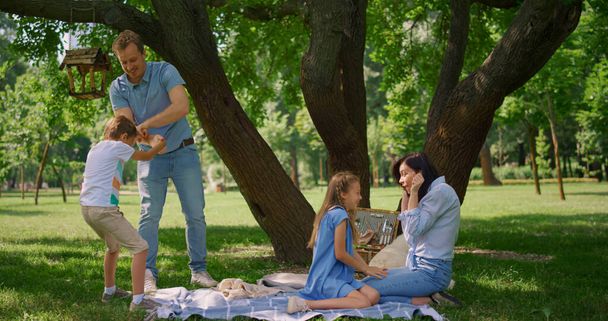 Ojciec trzyma małego synka na pikniku. Rodzice bawią się z dziećmi latem.. - Zdjęcie, obraz