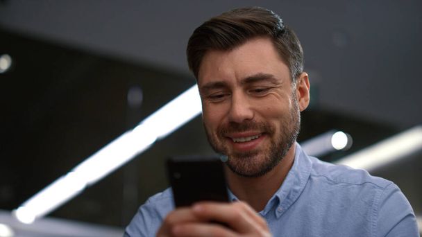 Uśmiechnięty biznesmen smsujący telefon na czacie online w korporacyjnym miejscu pracy - Zdjęcie, obraz