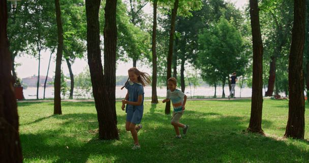Riendo niños corriendo en el soleado prado. Los niños felices juegan a ponerse al día en el parque. - Foto, Imagen