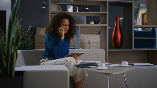 Fiatal afro-amerikai üzletasszony beszél telefonon az irodában. Távmunka-koncepció. - Fotó, kép