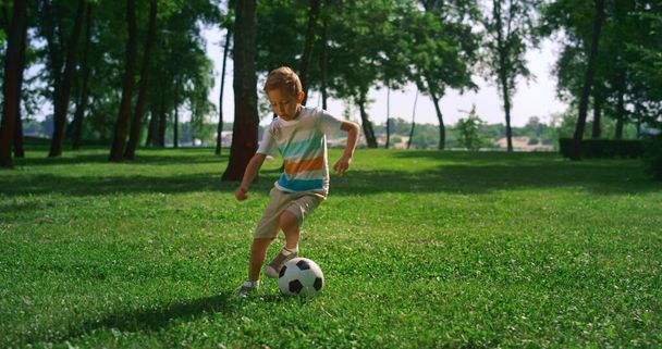 Енергійний хлопчик зігрівається перед футбольним матчем. Орієнтована гра для дітей на полі
. - Фото, зображення