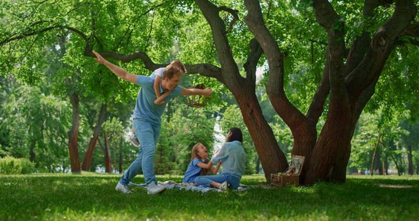 Smiling family have fun resting on nature. Parents play with childnen on picnic. - Photo, Image