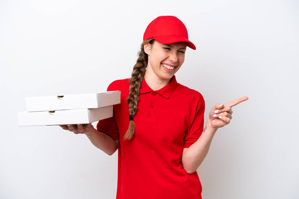 pizza delivery woman with work uniform picking up pizza boxes isolated on white background pointing finger to the side and presenting a product - Zdjęcie, obraz