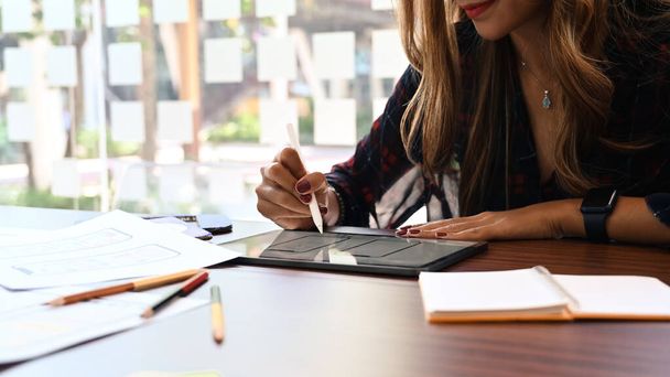 Młoda kobieta deweloper trzyma stylus długopis i pracuje na tablecie cyfrowym w biurze kreatywnym. - Zdjęcie, obraz