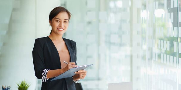 Портрет счастливой азиатки-предпринимательницы, улыбающейся и работающей в офисе. - Фото, изображение