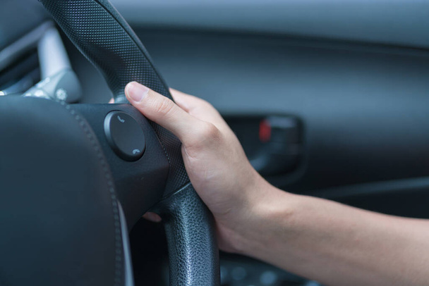 Human hand on the steering wheel drive car with buttons on the steering wheel for phone functions. - Foto, afbeelding