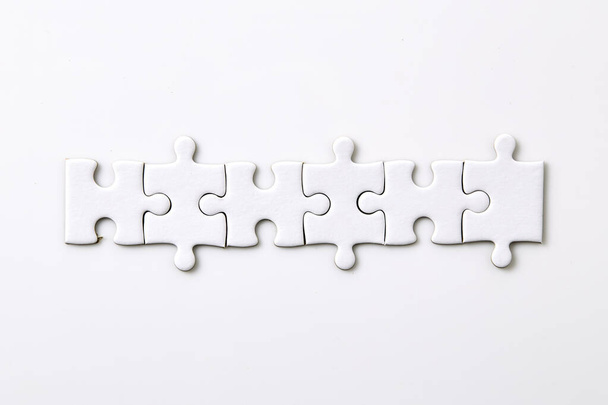 Sechs weiße, leere Puzzleteile auf weißem Hintergrund Verschmelzen verschiedener Elemente zu einem Ganzen - Foto, Bild