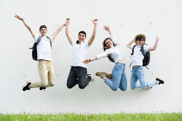 Szczęśliwa grupa nastolatków skacze i świętuje patrząc w kamerę. - Zdjęcie, obraz