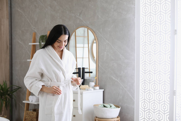 Beautiful young woman wearing soft white robe in bathroom - Foto, imagen
