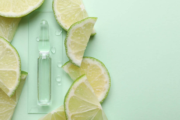 Pharmaceutical ampoule with medication and lime slices on turquoise background, flat lay. Space for text - Photo, Image