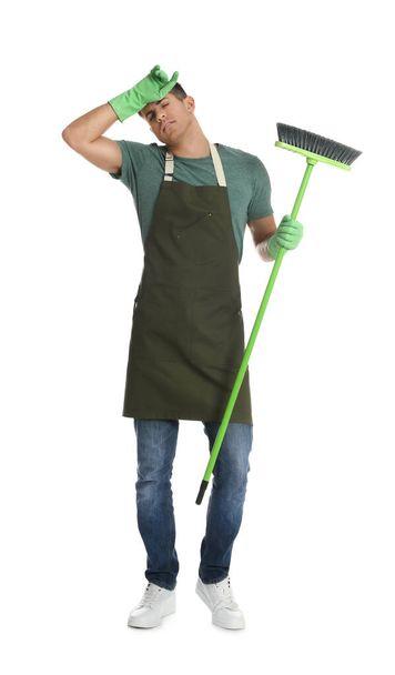 Tired man with green broom on white background - Foto, afbeelding