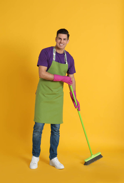 Man with green broom on orange background - Фото, зображення
