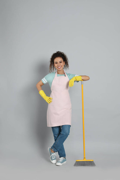 African American woman with yellow broom on grey background - Фото, изображение